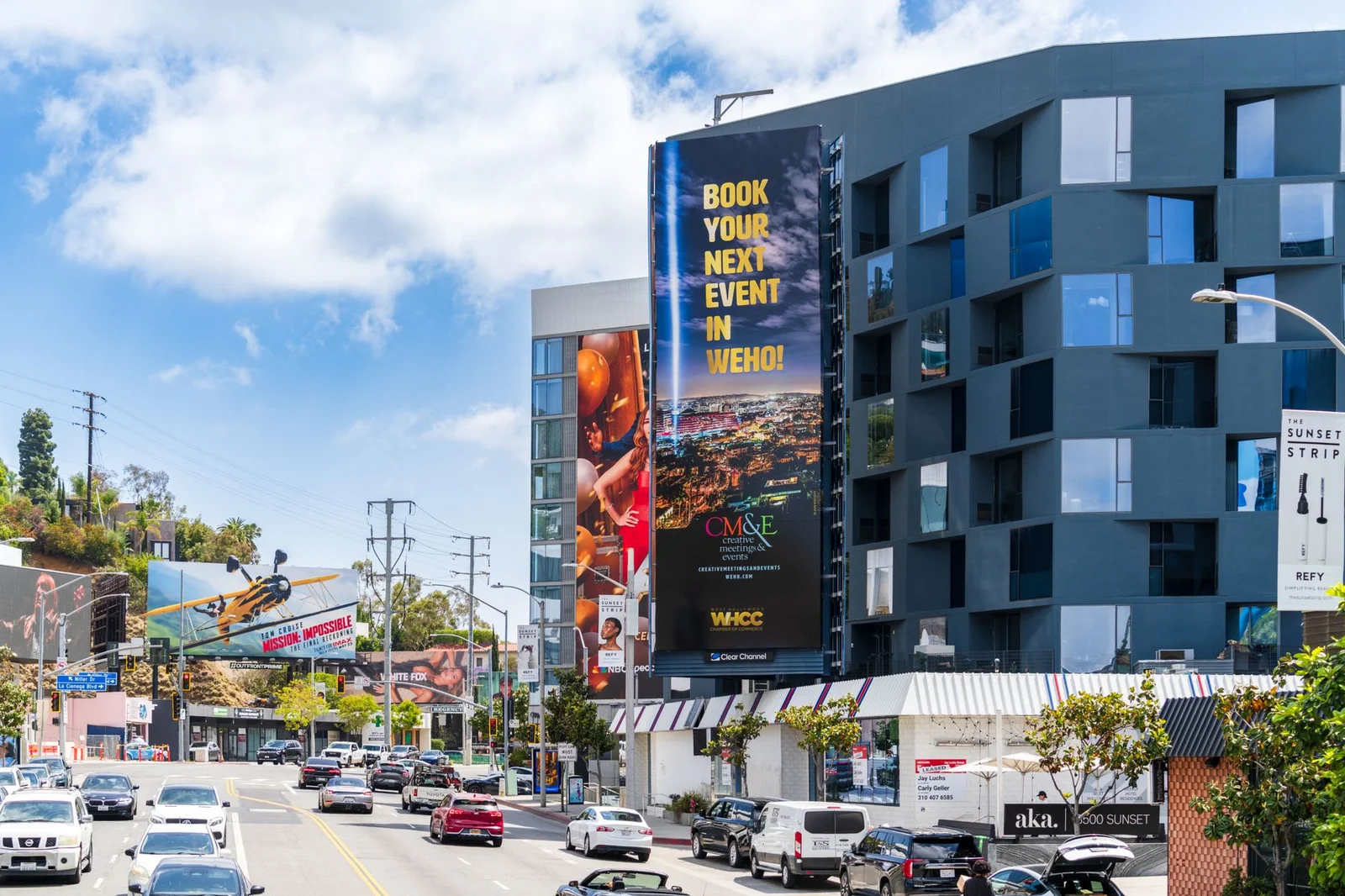 Colorful view of Sunset Boulevard with billboards and vehicles under a clear sky.
